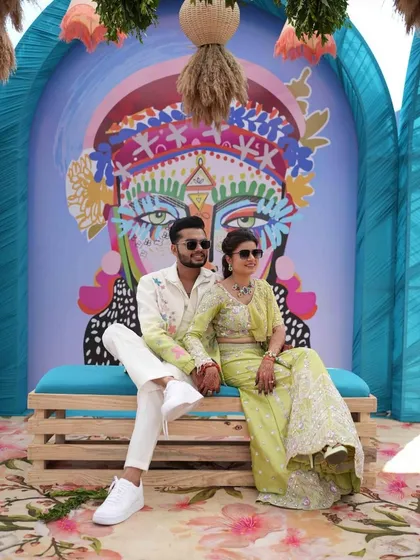 A relaxed moment for the couple at their carnival, posing in front of a colorful, artistic backdrop that perfectly matches their vibe.