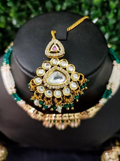 A close-up of a maang tikka from a rental set, featuring a triangular design with a large central polki stone.