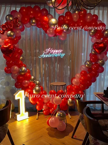 A clear, centered shot of the 1st-anniversary heart balloon arch, combining red, pink, and silver balloons with a central neon sign.