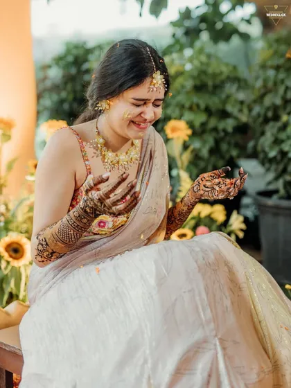 The bride's candid reaction during her Haldi, a moment of laughter and joy as she's covered in turmeric and petals.