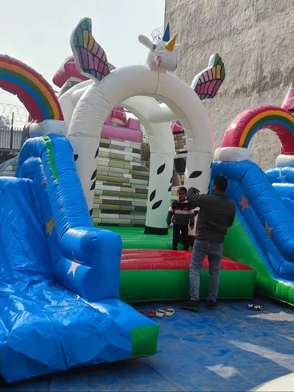A magical unicorn-themed bouncy castle with rainbows, wings, and two slides. This is a very popular design for girls' birthday parties and fantasy-themed events.