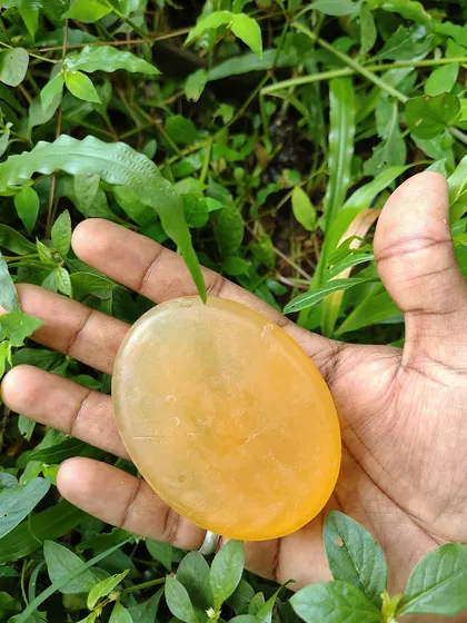 A close-up of my Lemon fragrance herbal soap against a backdrop of fresh greenery. The translucent quality shows the purity of the glycerin and natural extracts I use.