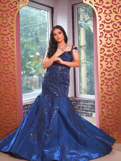 A full-length shot of the blue gown against an ornate archway.