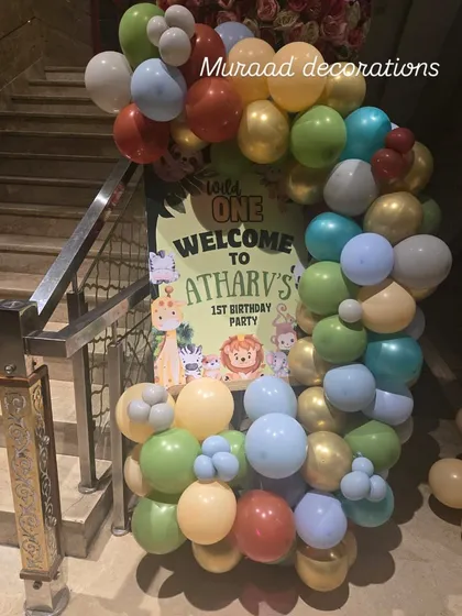A welcome sign for a jungle-themed first birthday party. A custom poster greets guests at the entrance, surrounded by a colorful balloon garland that sets a fun and wild tone.