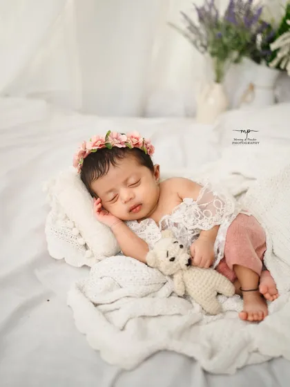 A tiny newborn cuddles with a small teddy bear, showcasing their delicate size. Using simple props helps to highlight the baby's features in a gentle, artistic way.