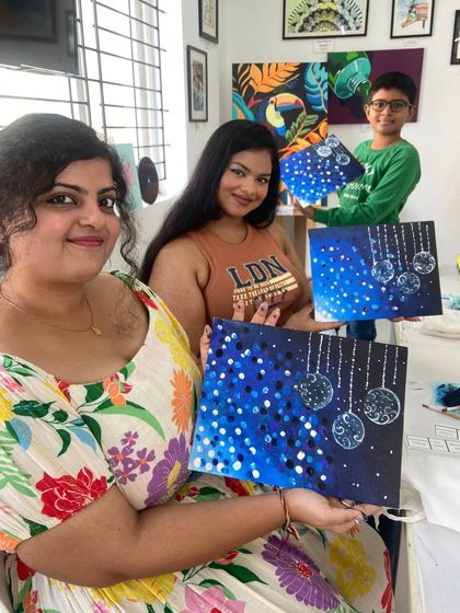 A group of participants shows off their finished canvases from a guided painting workshop. These sessions are perfect for beginners, as our instructors walk you through the painting step by step.