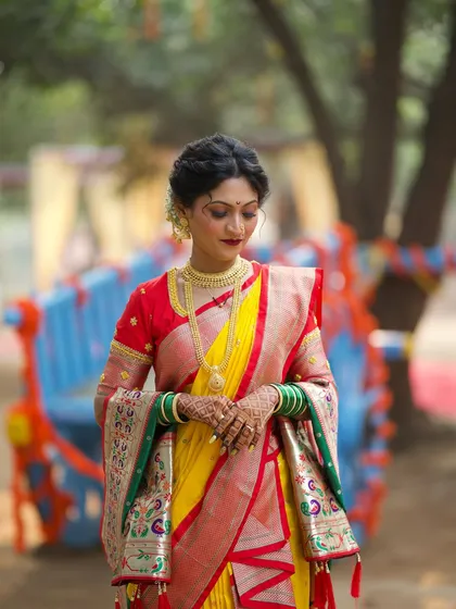 The bride stands gracefully, her traditional Nauvari saree perfectly draped. This image captures the complete look in a beautiful, rustic setting.