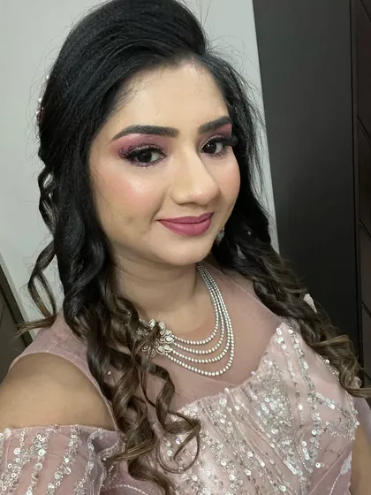 A glamorous HD party makeup look for a reception or cocktail event. The hairstyle is a voluminous half-updo with cascading curls, perfect for a night of celebration.