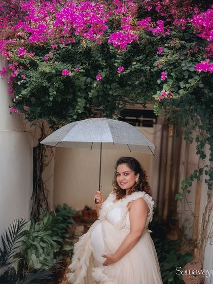 Even a little rain can't stop us from creating magic. The umbrella and the bougainvillea flowers create a charming and romantic setting for this maternity portrait.