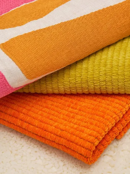 A stack of vibrant, textured fabrics from an Élitis collection. From bold, graphic prints to ribbed corduroy and plush weaves, this image celebrates the interplay of color and tactile surfaces in modern textile design.
