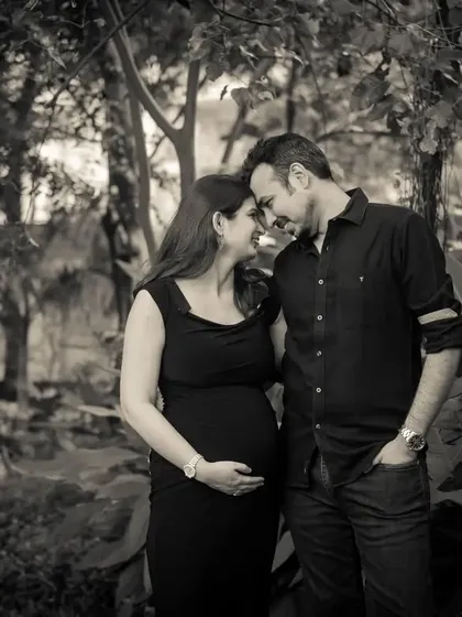 An intimate black and white portrait of a couple in a garden. Their foreheads are touching, creating a strong sense of connection and love.