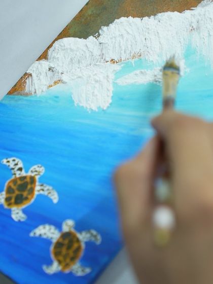 A close-up of a participant painting sea turtles on canvas. The fine details bring these gentle creatures to life.