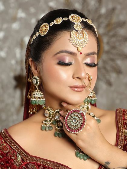 A truly regal bride. This look features a stunning matha patti and intricate jewelry, paired with soft pink eyeshadow and a defined eye to create a majestic yet gentle appearance.