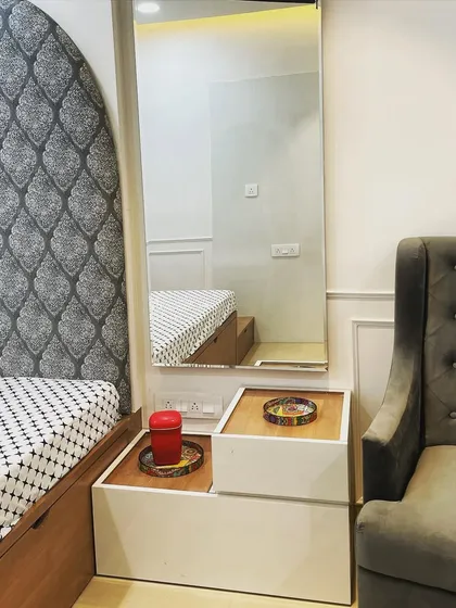 This is a smart, space-saving solution we designed. The unit functions as both a bedside table with handleless drawers and a compact dressing table with a full-length mirror, perfect for smaller bedrooms where every inch counts.