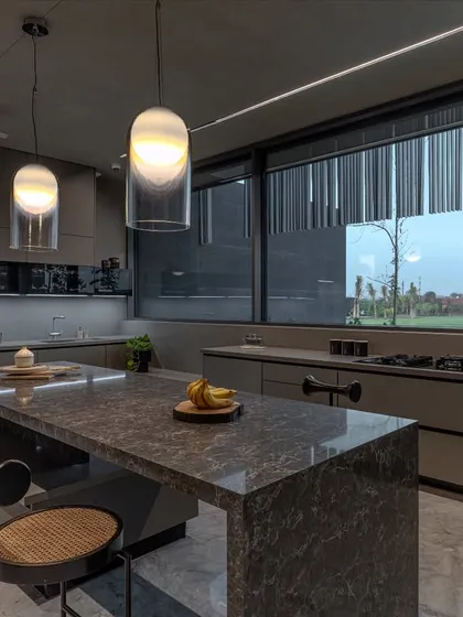 Expansive windows in this farmhouse kitchen draw in natural light and offer views of the surrounding landscape, making the space feel open and connected to the outdoors.