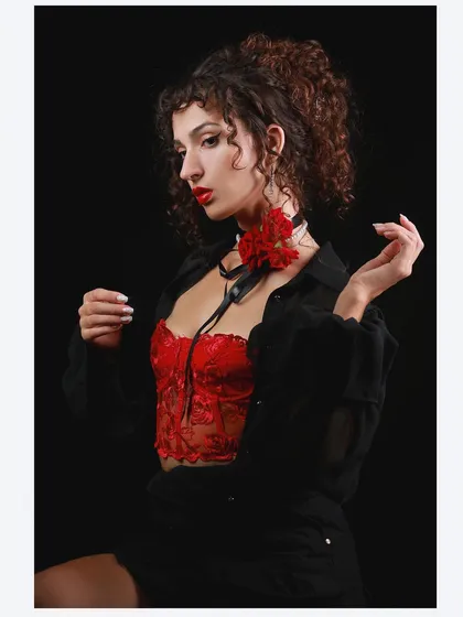 A vintage-inspired portrait of a model in a red corset and black shirt, channeling old Hollywood glamour.