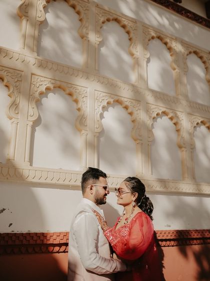 A close-up of the couple sharing an intimate moment against a beautifully carved wall. The warm sunlight highlights their expressions and the rich texture of their traditional outfits.