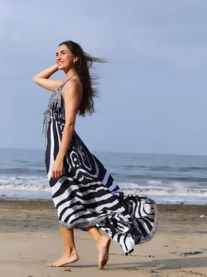 A dynamic shot of a woman on the beach, her dress catching the wind, creating a sense of movement and freedom.