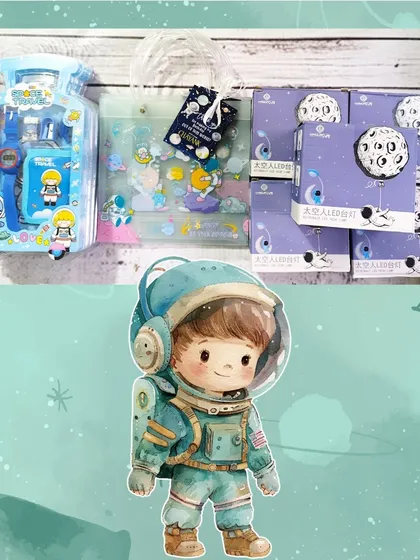 A flat lay of the space-themed hamper items, showing the stationery set, the favor bag, and the boxes for the astronaut desk lamps.