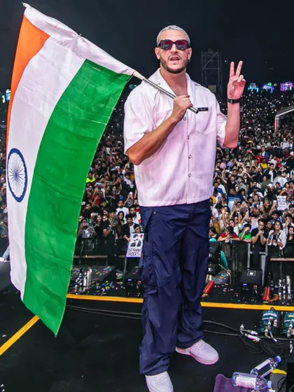 DJ Snake holds the Indian flag, giving a peace sign to the thousands of fans in the audience.