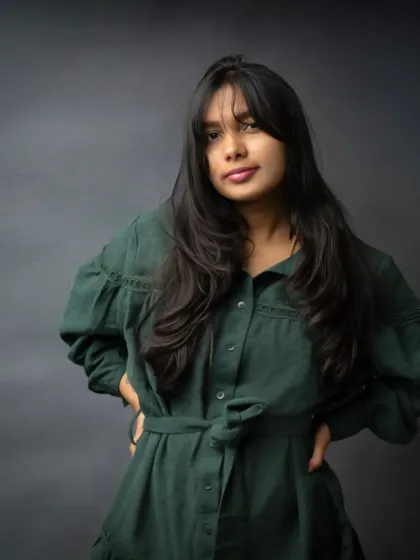 A confident and direct portrait against a classic moody backdrop. Her pose and direct gaze convey a quiet strength, making for a powerful and engaging image.