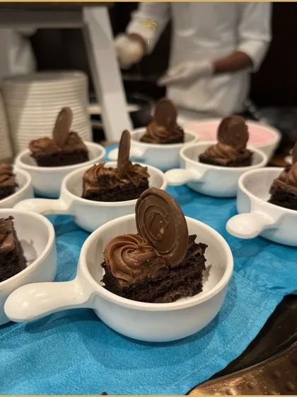 Decadent chocolate brownie bites topped with chocolate mousse and a chocolate disk. Served in individual handle-cups, they are a rich and indulgent treat for all chocolate lovers.