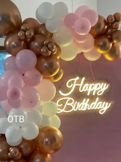 A detail shot of the 'Happy Birthday' neon sign and the top of the balloon arrangement.