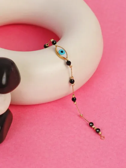 An elegant shot of an evil eye bracelet draped over a white ceramic prop with stones. This creative composition highlights the delicate beauty of the jewelry.