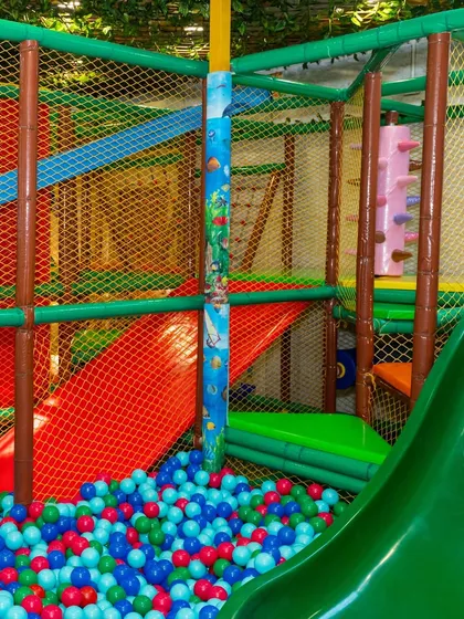 A view from inside the ball pit looking up at the slides and climbing structure, showing the scale and excitement of the play area.