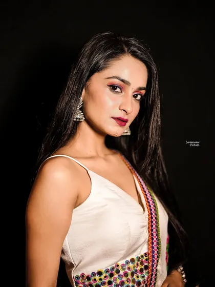 A powerful studio portrait for Navratri. The model's direct gaze, combined with the traditional white lehenga and silver jewelry, creates a look of modern confidence.