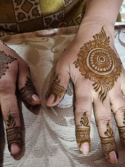 A simple yet beautiful design for party guests. This features a mandala on the back of the hand and small, leafy motifs on the fingertips.