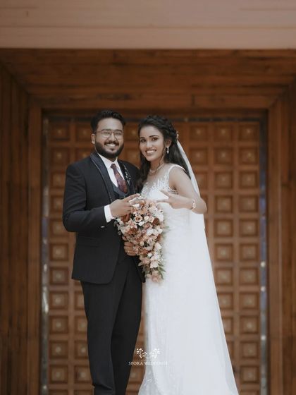 The bride and groom sharing a fun, happy moment in front of the large wooden doors of the church.
