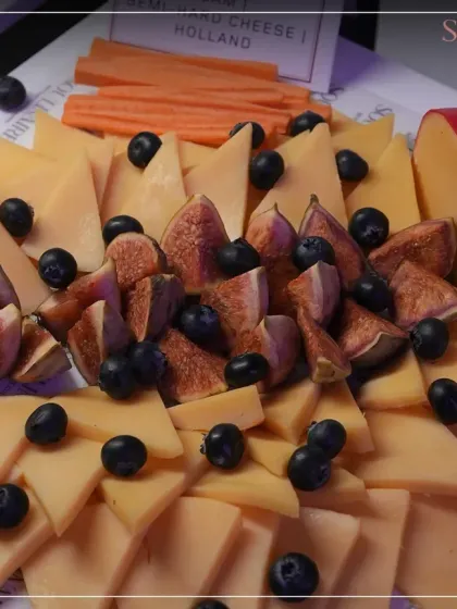 A beautiful cheese platter featuring Gouda, fresh figs, and blueberries. Our tasting selections are curated to offer a journey through the world's finest cheeses.