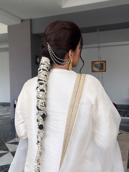 This back view showcases the full length of the statement bridal braid. Learning how to securely attach these large accessories is a crucial skill for any professional hairstylist.
