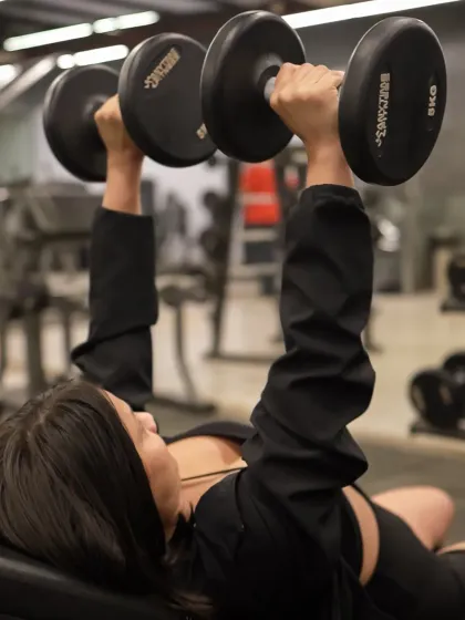 Feel the power of a focused workout. This member is performing a dumbbell bench press, a fundamental exercise for building upper body strength, in our well-equipped free weights area.