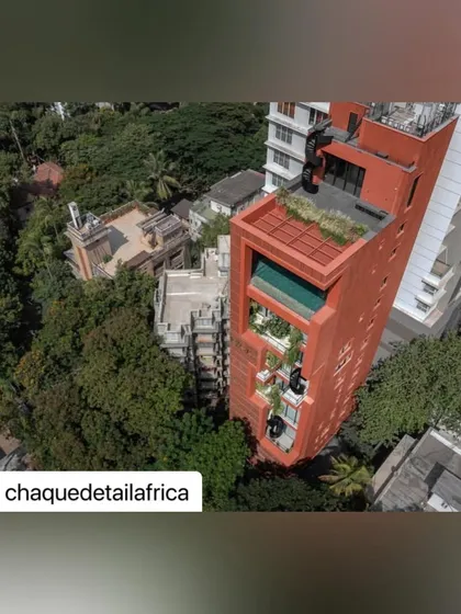 An aerial perspective of the Sarvasva tower shows how it is nestled within the green canopy of the neighborhood. The rooftop garden and green terraces make it a prominent feature of the local landscape.
