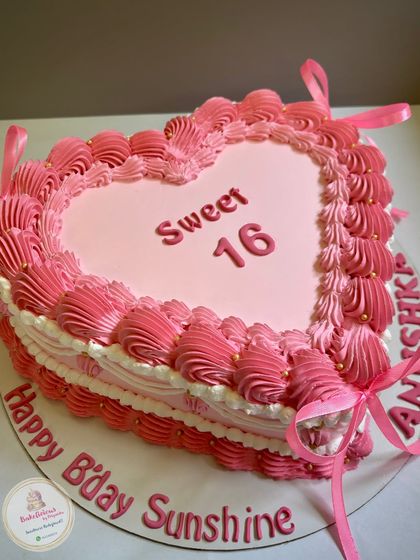 A pretty pink heart-shaped cake for a Sweet 16 celebration. I used delicate piping techniques to create an ombre effect and finished it with ribbons and gold pearls.