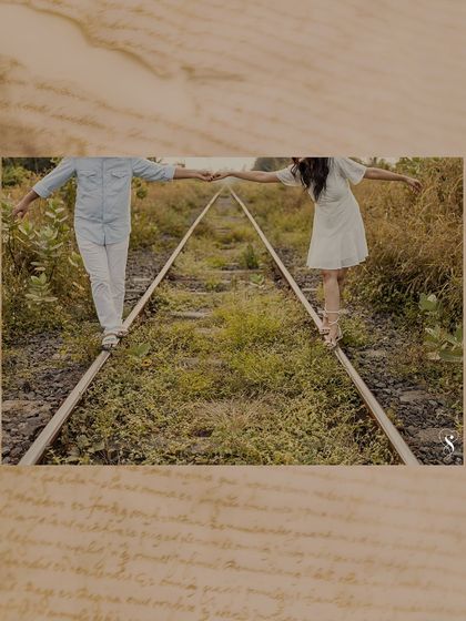 A creatively framed shot of the couple balancing on the railway tracks. This artistic edit adds a nostalgic, storybook feel to their adventurous pre-wedding theme.