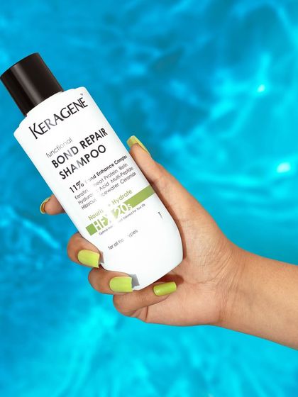 A hand holding the shampoo bottle against a vibrant blue water background. This lifestyle shot feels fresh, clean, and perfect for summer.