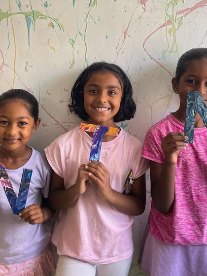 A group of girls show off the fluid art letter magnets they created. This is a fun, quick, and satisfying project for any art party.