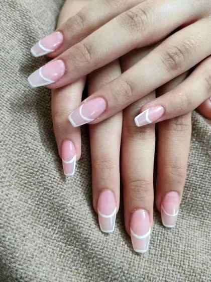 A minimalist and modern outlined French manicure, where a thin white line traces the shape of the nail on a natural pink base.