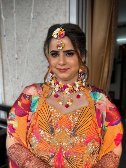 A vibrant Haldi look with a colorful printed jacket. The floral jewelry adds a traditional and festive touch.