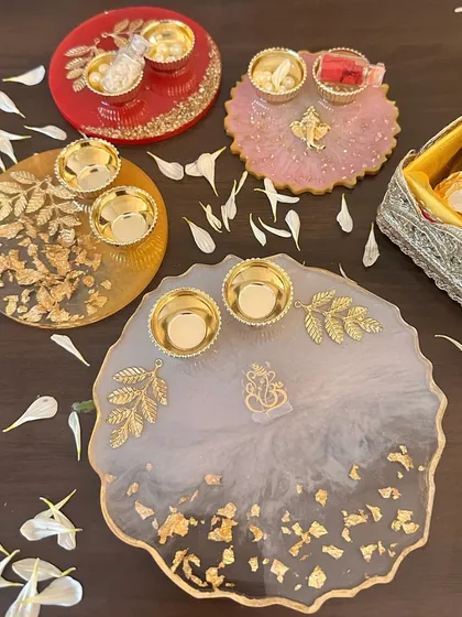 A stunning array of my handcrafted resin Rakhi thaalis. Available in red, pink, yellow, and white, each thaali is adorned with gold leaf details and comes with katoris for roli and chawal, blending artistry with tradition.