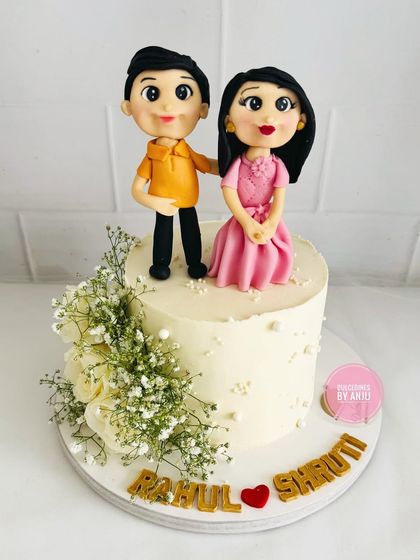 A sweet and simple Roka celebration cake. This design features delicate fresh flowers and adorable, personalized fondant toppers of the happy couple.