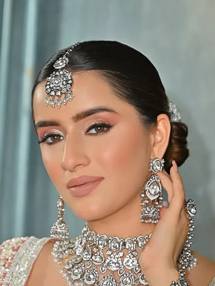 A close-up on the model's face, showing how a neat, pulled-back hairstyle allows the statement jewellery and makeup to shine.