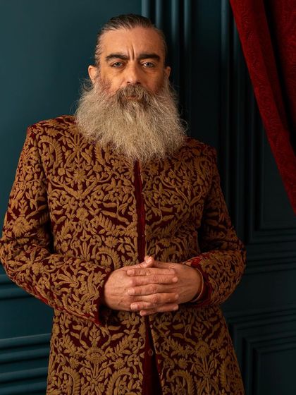 This maroon velvet sherwani with all-over gold embroidery is the epitome of regal elegance. It’s a statement piece that fuses traditional motifs with a modern, tailored fit.