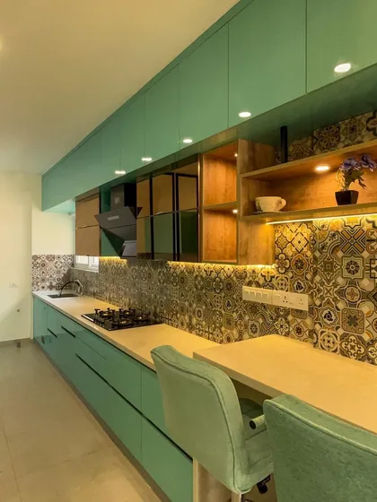 This long shot of the galley kitchen highlights the precision of our factory-made modular units. We ensure uniform cabinet finishes and perfect alignment over long spans, complete with integrated open shelving and under-cabinet lighting.