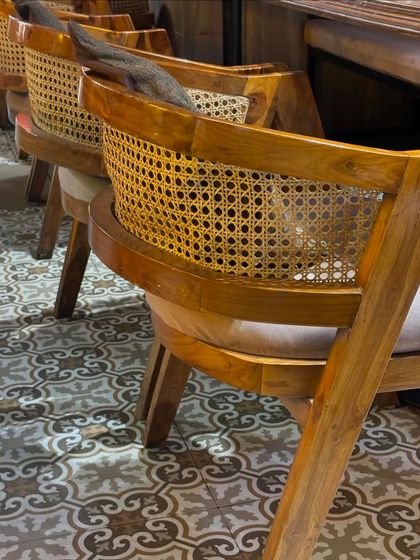 Another view of the cane chairs, showing the beautiful curvature of the backrest and the quality of the weaving. This design is timeless and adds a warm, inviting feel to any space.