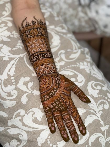 A full view of a classic Indian mehendi design, covering the hand and forearm. The pattern includes traditional elements like mandalas and checkered fills.