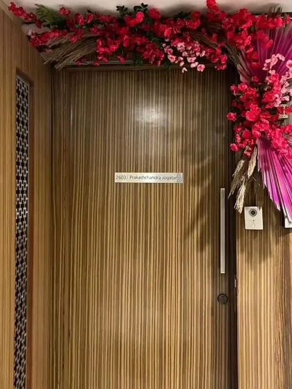 A modern floral arrangement for a housewarming, using vibrant pink flowers and dried palms to create a stylish welcome at the front door.